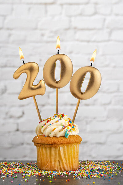 Золотая именинная свеча номер 200 с кексом - белый блочный фон стены