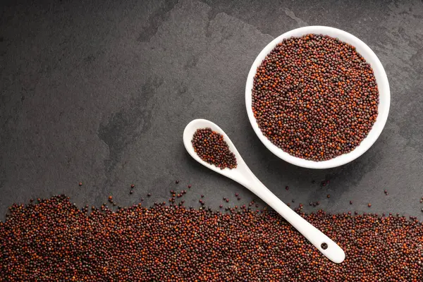 stock image Brassica juncea - Brown mustard seeds in bowl and spoon.