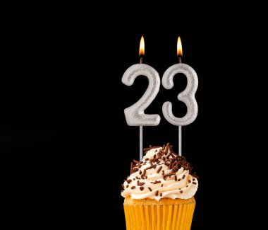 Siyah arkaplanda doğum günü pastası - 23 numara şekilli mumlar.