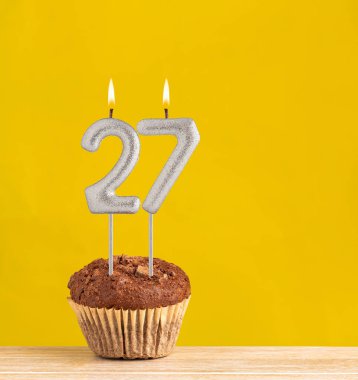 27 numaralı doğum günü mumu - Sarı arka planda çikolatalı kek.
