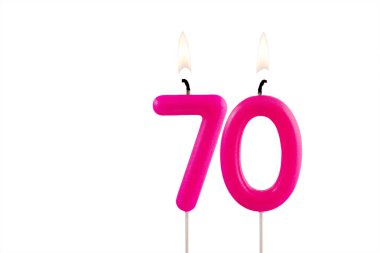 70 numaralı pembe doğum günü mumu beyaz arka planda yanıyor.