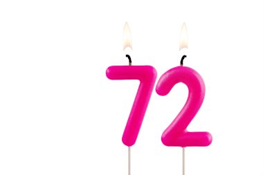 72 numaralı pembe doğum günü mumu beyaz arka planda yanıyor.