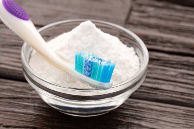 Kabın içinde kabartma tozu ve diş fırçası - ahşap arka plan.