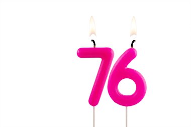 76 numaralı pembe doğum günü mumu beyaz arka planda yanıyor.