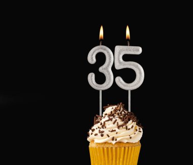 Siyah arkaplanda doğum günü pastası - 35 numara şekilli mumlar.
