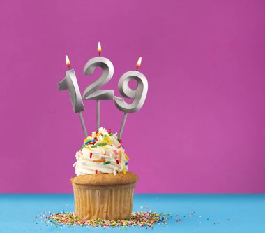 129 numaralı doğum günü mumlu kek - Mavi ve mor arka planda yıldönümü kartı