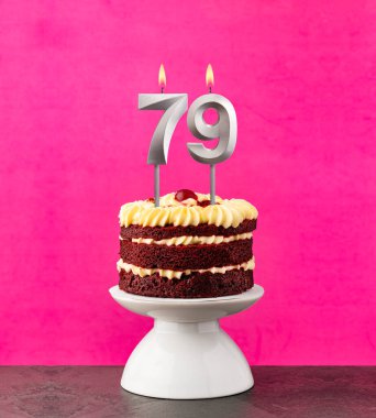 79 numaralı mumlu doğum günü pastası fuşya arka planında kırmızı kadife..