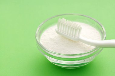 Diş fırçası ve kabın içindeki kabartma tozu - yeşil arka plan.