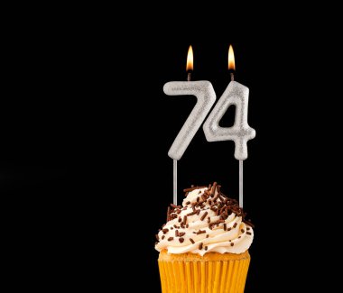 74 numara şekilli mumlar - Siyah arkaplanda doğum günü pastası.