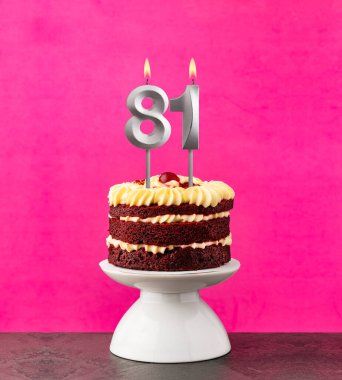 81 numaralı mumlu doğum günü pastası fuşya arka planında kırmızı kadife..