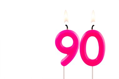 90 numaralı pembe doğum günü mumu beyaz arka planda yanıyor.