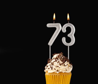 Siyah arkaplanda doğum günü pastası 73 numara şekilli mumlar..