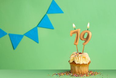 79 numaralı mumlu doğum günü kartı mavi flama ile yeşil arka planda kek..