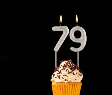 Siyah arkaplanda doğum günü pastası 79 numara şekilli mumlar..