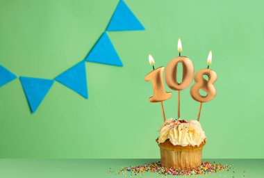 108 numaralı mumlu doğum günü keki - mavi flama ile yeşil arkaplan.