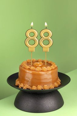 Yeşil arka planda 88 numaralı doğum günü mumuyla nefis bir pasta..