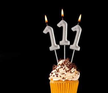 Siyah arkaplanda doğum günü pastası - 111 numara şekilli mumlar.