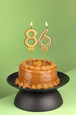 Lezzetli pasta, dulce de leche - 86 numaralı doğum günü mumu yeşil arka planda..