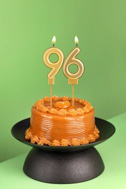 Yeşil arka planda 96 numaralı doğum günü mumuyla nefis bir pasta..