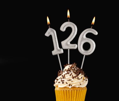 126 numara şekilli mumlar - Siyah arkaplanda doğum günü pastası.