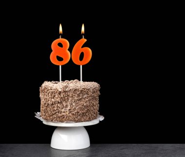 86 numaralı mumlu doğum günü kartı - Siyah arka planda çikolatalı pasta.