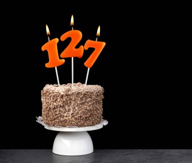 127 numaralı mumlu doğum günü pastası. Siyah arka planda yıldönümü kartı..