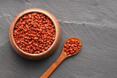 Red organic annatto seeds in spoon and bowl - Bixa Orellana clipart