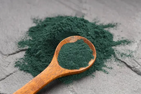 Bir kaşıkta organik yeşil spirulina tozu - besin takviyesi.