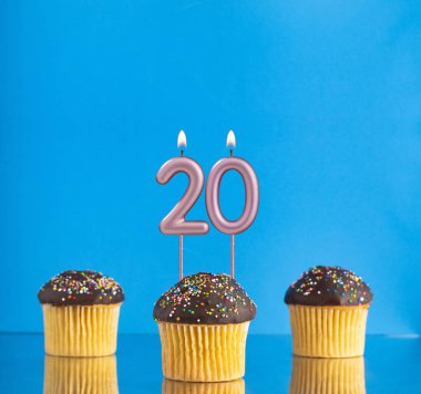 20 numarayla doğum günü mumu - Mavi arka planda üç kek.