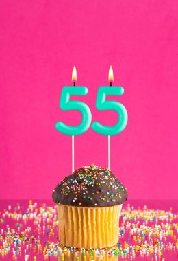 55 numaralı mumlu doğum günü keki fuşya arka planında kutlama kartı.