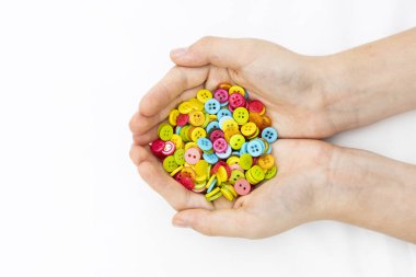 Bir kadının ellerinde çeşitli renklerde sayısız düğme var..