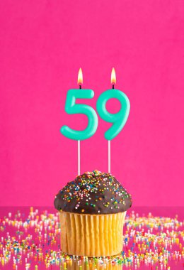 59 numaralı mumlu doğum günü keki fuşya arka planında kutlama kartı.