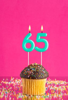 65 numaralı mumlu doğum günü keki fuşya arka planında kutlama kartı..