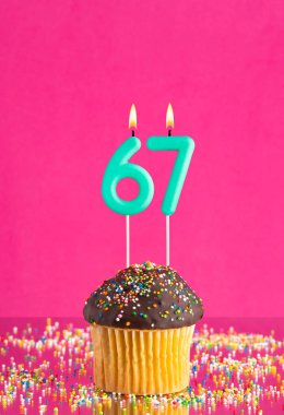 67 numaralı mumlu doğum günü keki fuşya arka planında kutlama kartı.