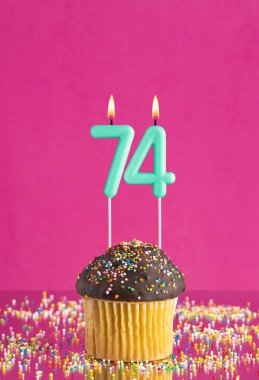 Kekli doğum günü kartı ve 74 numaralı mum - Pembe arka plan.