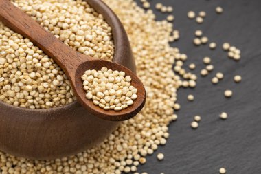 Bir kaşık ve kâsede organik beyaz kinoa tohumları - Chenopodium kinoa