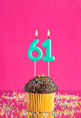 61 numaralı mumlu doğum günü keki fuşya arka planında kutlama kartı.