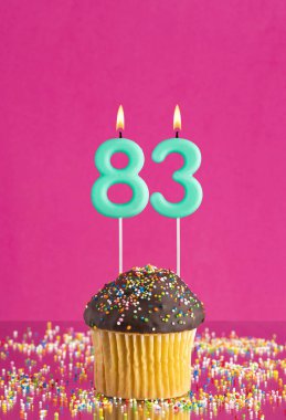 83 numaralı mumlu doğum günü keki fuşya arka planında kutlama kartı