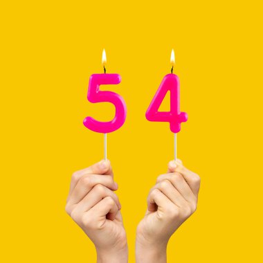 Elleri doğum günü mumlarını tutarken 54 numara - Sarı arka plan