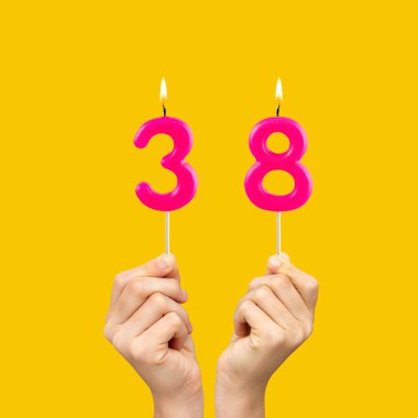 38 numaralı doğum günü mumlarını tutan eller - Sarı arkaplan