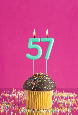 57 numaralı mumlu doğum günü keki fuşya arka planında kutlama kartı.