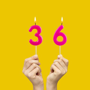 36 numaralı doğum günü mumlarını tutan eller - Sarı arkaplan