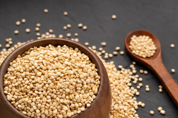 Kaşık ve kâse içinde çiğ beyaz kinoa tohumları - Chenopodium kinoa