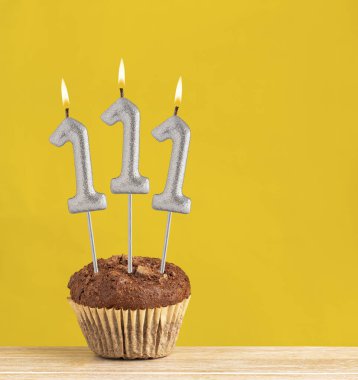 111 numara doğum günü mumu - Sarı arka planda çikolatalı kek.