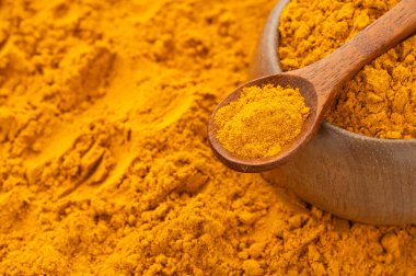 Bir kaşık ve kâsede organik zerdeçal tozu Curcuma longa