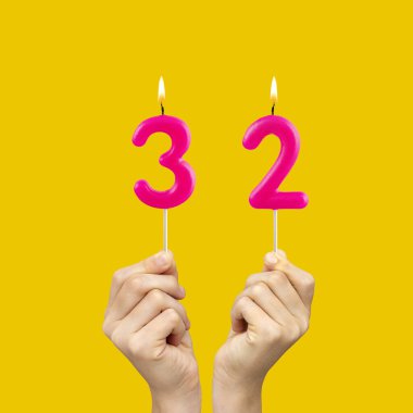 32 numaralı doğum günü mumlarını tutan eller - Sarı arkaplan
