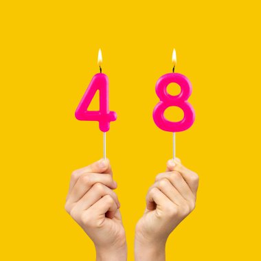 48 numaralı doğum günü mumlarını tutan eller - Sarı arka plan