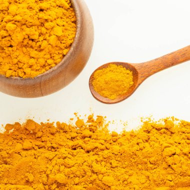 Bir kaşık ve kâsede organik zerdeçal tozu Curcuma longa