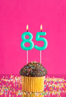 85 numaralı mumlu doğum günü keki fuşya arka planında kutlama kartı