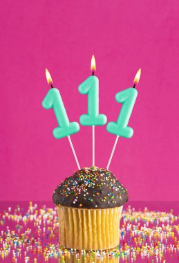 111 numaralı mumlu doğum günü keki fuşya arka planında kutlama kartı.